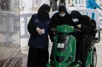 A female employee helping one of the visitors of the Grand Mosque use the electric scooter. (SPA)