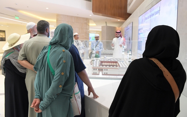 Several visitors to the Architecture of Prophet&#039;s Mosque Exhibition listening to an explanation about one of the exhibits. (SPA)