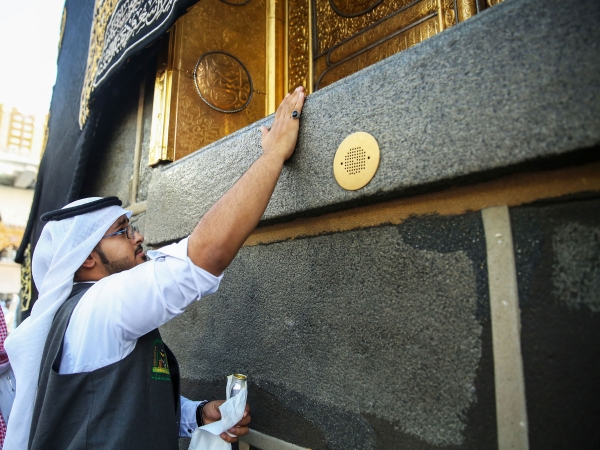 An employee perfuming the walls of the Kaaba. (Saudipedia)