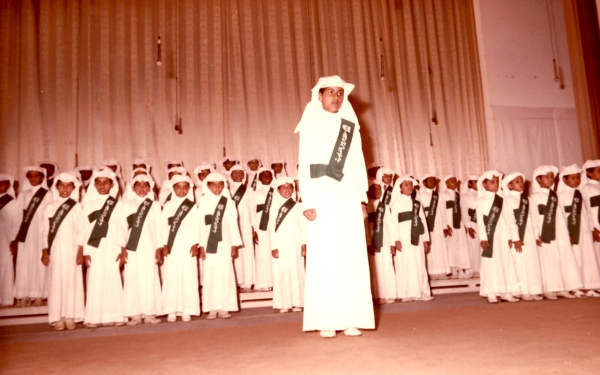 A picture of a group of students performing a segment on stage in front of Abdulaziz Al-Khowaiter, Minister of Education, in 1982. (Darah)