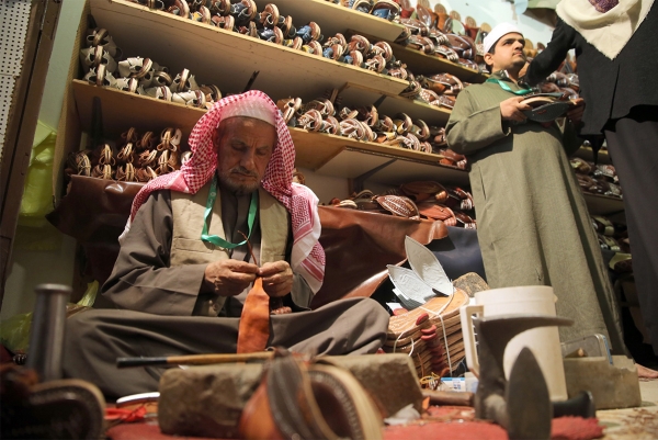 One of the craftsmen works in the manufacture of leather shoes. (Saudipedia)