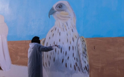 A Saudi female artist working on a mural of a falcon. (SPA)