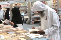 An elderly man browsing a book at Riyadh International Book Fair. (Saudipedia)