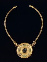 A gold necklace adorned with gemstones and pearls, featuring an engraved human face. (Saudi Commission for Tourism and Antiquities)