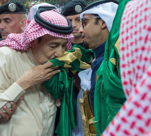 Le roi Salmane embrassant le drapeau saoudien lors de la cérémonie de l'Ardah saoudienne au Festival national du patrimoine et de la culture en 2016. (SPA)