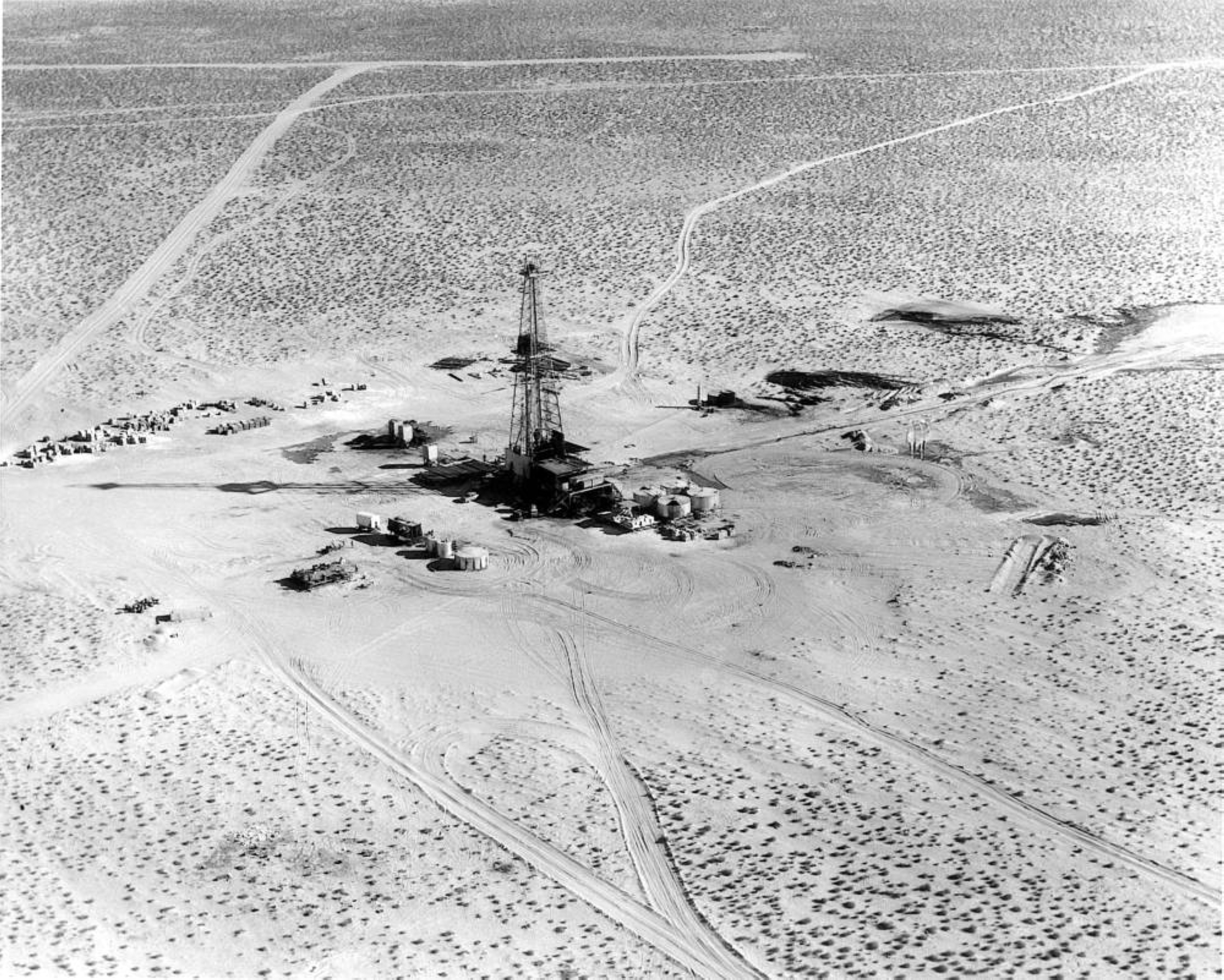 Foreur de pétrole affilié à Aramco forant un puits dans le désert. Saudi Aramco. Fondation du Roi Abdelaziz pour la recherche et les archives (Darah)