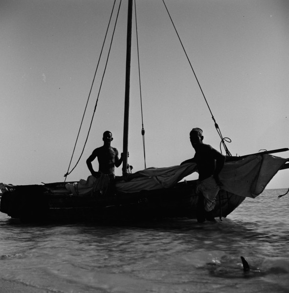 صورة قديمة توثق لربان ورفيقه وهما يستعدان لانطلاق قاربهما في البحر. (دارة الملك عبدالعزيز)