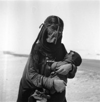 صورة قديمة لامرأة من البادية بلبس العباءة والبرقع.ايلو بيتاجيلي. (دارة الملك عبدالعزيز)