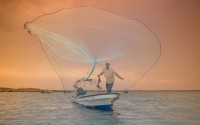 صياد سمك يرمي شباكه داخل البحر خلال موسم الكنة. (هذه السعودية)