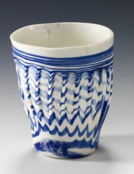 كأس مصنوعة من الزجاج الأبيض وعليها زخارف باللون الأزرق. (الهيئة العامة للسياحة والآثار)