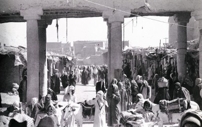 سوق العلف إحدى أسواق الرياض تظهر ساحاتها ممتلئة بالمرتادين والباعة كما تظهر بعض الدكاكين الصغيرة عام  1370هـ/1950م. (دارة الملك عبدالعزيز)