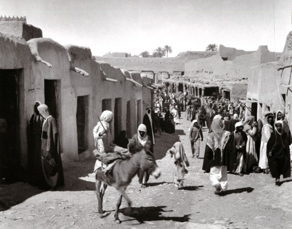 سوق الديرة وهي السوق الرئيسة قديما بالرياض تظهر فيها الدكاكين الطينية وبعض مرتادي السوق عام 1357هـ/1937م. (دارة الملك عبدالعزيز)
