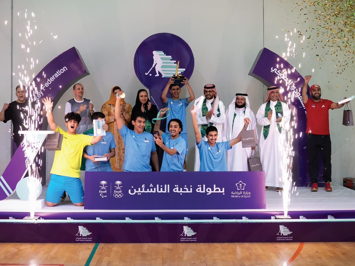 مجموعة من الأشخاص على منصة التتويج يحملون كأس البطولة